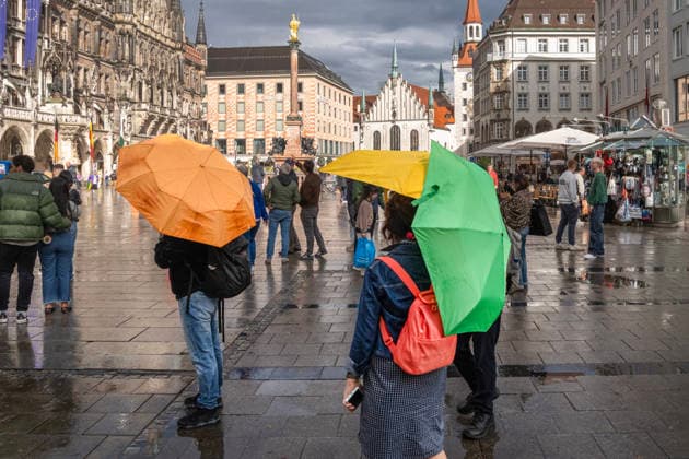 Nach Wolkenbruch und Gewitter blinzelt schon wieder die Sonne durch eine Wolkenlücke und taucht den Marienplatz in ein wunderbares Licht, Passanten mit bunten Regenschirmen, München, 6. Mai 2026 Deutschland, München, 6. Mai 2026, nach Wolkenbruch scheint schon wieder die Sonne über dem Marienplatz, Passanten mit bunten Regenschirmen, zuvor heftiger Starkregen mit Gewitter, Mitwocnachmittag um 17:30 Uhr, Innenstadt, Wirtschaft, Wetter, Unwetter, Frühling, Bayern