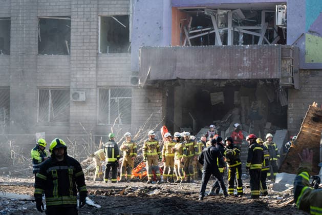 Rescuers from the State Emergency Service stand outside a building damaged by a Russian missile and drone strike in Kyiv, Ukraine, on May 14, 2026. Russia launched a massive attack on the Ukrainian capital, deploying more than 670 strike drones and 56 missiles of various types. The attack damaged 11 multi-storey residential buildings, cars, a supermarket, two car dealerships, two petrol stations, a business centre, and a service station. At least five people were killed, and 40 people were injured, including an infant. (Photo by Danylo Antoniuk Ukrinform) Kyiv comes under massive attack of Russian drones and missiles Copyright: xDanyloxAntoniukx