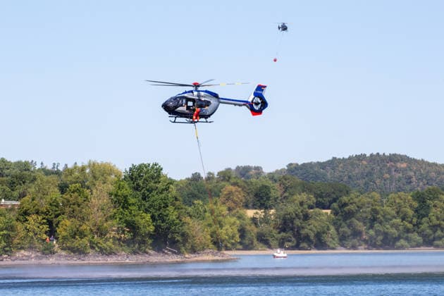 Plauen - Polizeihubschrauber unterstützen Löscharbeiten bei Waldbrand in Plauen Plauen, Meßbach, Messbach, Vogtland, Sachsen, Waldbrand, Vegetationsbrand, Feuerwehr, Löscharbeiten, Polizeihubschrauber, Polizei Sachsen, sächsische Polizei, H145, Airbus H145, Löschhubschrauber, Hubschrauber, Luftunterstützung, Bambi Bucket, Löschwasserbehälter, Außenlast, Wasseraufnahme, Wasserabwurf, Talsperre Pirk, Pirk, Katastrophenschutz, Einsatz, Brandbekämpfung, Glutnester, wildfire, forest fire, firefighting helicopter, aerial firefighting Plauen Sachsen Deutschland Copyright: xEHLxMediax 20260812_plauen-waldbrand-hubschrauber_17