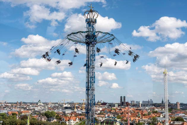 Oktoberfest 2026, Blick vom Riesenrad auf den BayernTower, am Horizont die Stadt München mit ihrem Wahrzeichen der Frauenkirche, Wiesn-Start bei strahlendem Sonnenschein und Temperaturen bis 24 Grad, bestes Wiesnwetter, Eröffnungstag, 19. September 2026 Deutschland, München, 19. September 2026, Oktoberfest 2026, Blick vom Riesenrad auf den BayernTower, am Horizont die Stadt München mit ihrem Wahrzeichen der Frauenkirche, Wiesn-Start bei strahlendem Sonnenschein und Temperaturen bis 24 Grad, mittags um 13, kurz nach der Eröffnung, blauweißer Himmel, bestes Wiesnwetter, typisch bayerisch, Volksfest, Bayern,