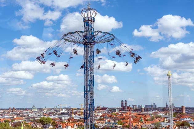 Oktoberfest 2026, Blick vom Riesenrad auf den BayernTower, am Horizont die Stadt München mit ihrem Wahrzeichen der Frauenkirche, Wiesn-Start bei strahlendem Sonnenschein und Temperaturen bis 24 Grad, bestes Wiesnwetter, Eröffnungstag, 19. September 2026 Deutschland, München, 19. September 2026, Oktoberfest 2026, Blick vom Riesenrad auf den BayernTower, am Horizont die Stadt München mit ihrem Wahrzeichen der Frauenkirche, Wiesn-Start bei strahlendem Sonnenschein und Temperaturen bis 24 Grad, mittags um 13, kurz nach der Eröffnung, blauer Himmel, bestes Wiesnwetter, typisch bayerisch, Volksfest, Bayern,