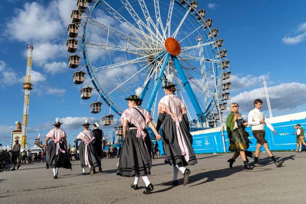 Oktoberfest 2026, Wiesnbesucherinnen in Tracht bummeln bei strahlendem Sonnenschein über das Festgelände, vorbei am Riesenrad, schönstes blauweißes Wiesnwetter, München, 22. September 2026 Deutschland, München, 22. September 2026, Oktoberfest 2026, Wiesnbesucherinnen in Tracht bummeln bei strahlendem Sonnenschein über das Festgelände, vorbei am Riesenrad, schönstes blauweißes Wiesnwetter, bei Temperaturen bis 19 Grad, nachmittags um 17:30 Uhr, schönes Wiesnwetter, typisch bayerisch, Volksfest, Bayern,