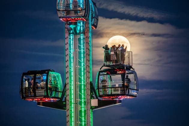 Der Vollmond, auch Erntemond genannt, leuchtet hinter dem SkyLift auf dem Oktoberfest, Wiesnbesucher in den Gondeln und auf der Freifläche machen Fotos mit ihren Smartphones, München, 26. September 2026 Deutschland, München, 26. September 2026, der Vollmond, auch Erntemond genannt, leuchtet hinter dem SkyLift auf dem Oktoberfest, Wiesnbesucher in den Gondeln und auf der Freifläche machen Fotos mit ihren Smartphones, Theresienwiese, fast wolkenfreier Abendhimmel, um 19:25 Uhr, Bayern
