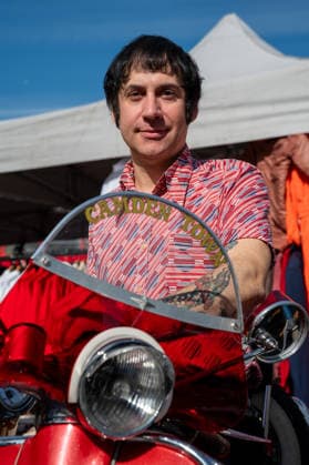 September 26, 2026, London, United Kingdom: An attendee at the King™s Cross Classic Car Boot Sale in London poses for photographs while sitting on a vintage Italian scooter. The Kings Cross Classic Car Boot Sale returned to Granary Square and Stable Street, King™s Cross, London, for its 11th year. Held several times throughout the year, the event brings together vintage fashion, second-hand clothing, jewellery, homewares, collectables and vinyl records alongside classic cars, motorcycles and commercial vehicles. Visitors browsed stalls and traders, with many making a special effort to dress in period clothing inspired by the 1950s, 1960s and 1970s.continuing a tradition associated with the event. London United Kingdom - ZUMAs197 20260926_aaa_s197_388 Copyright: xJamesxWilloughbyx