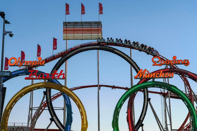 Olympia-Looping mit Deutschlandflagge auf dem Oktoberfest, Symbolfoto Münchner Olympia-Bewerbung hat den Zuschlag vom DOSB erhalten, München, 27. September 2026 Deutschland, München, 27. September 2026, die Achterbahn Olympia-Looping mit Deutschlandflagge auf dem Oktoberfest, ein Zug fährt abends durch die beleuchtete Bahn, Symbolfoto die Münchner Olympia-Bewerbung hat den Zuschlag vom DOSB erhalten, Sonntagabend um kurz vor 19 Uhr, Blaue Stunde, Bayern