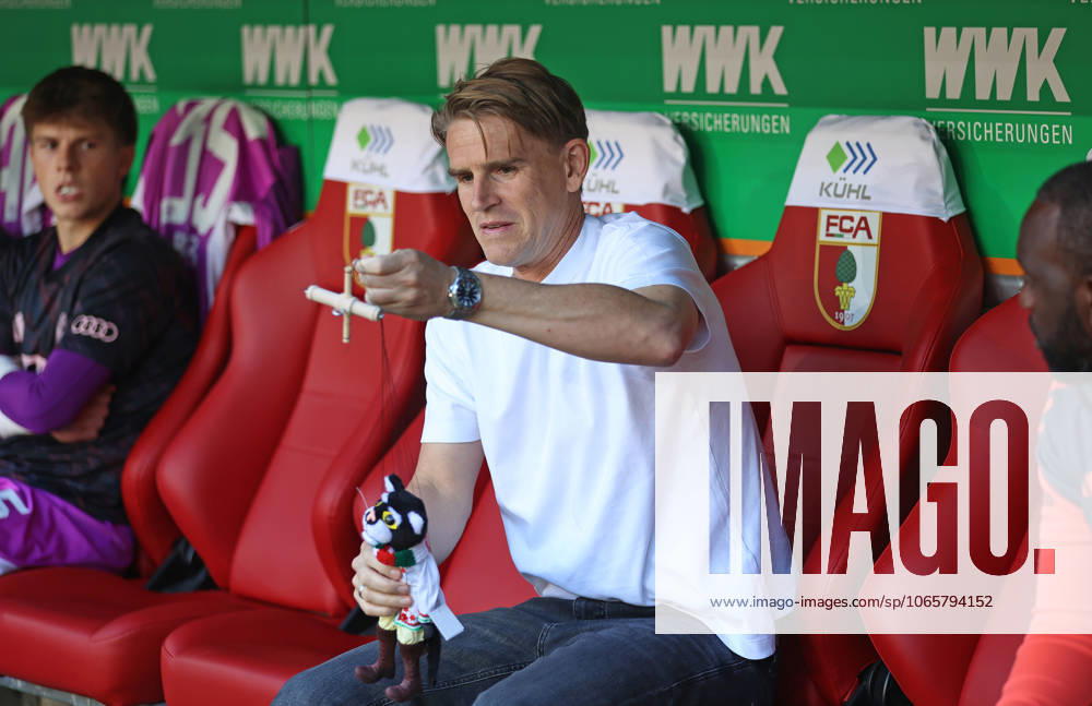 Fussball, Herren, Saison 2025 2026, FC Augsburg - FC Bayern München, Bundesliga, WWK Arena Christoph Freund, Sportdirektor (FC Bayern München) mit dem Gastgebergeschenk aus der Augsburger Puppenkiste, Kater Mikesch DFL DFB regulations prohibit any use of photographs as image sequences and or quasi-video
