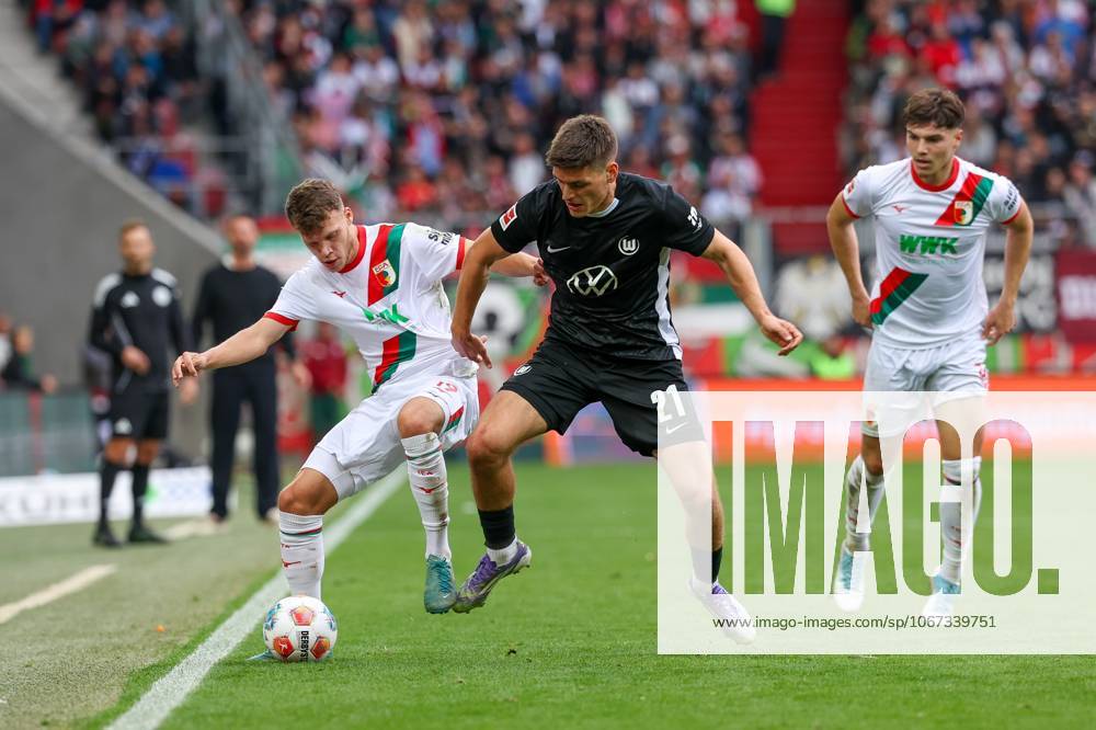 Im Zweikampf, Aktion, mit Robin Fellhauer 19 (FC Augsburg), Joakim Maehle 21 (VfL Wolfsburg), Mert Koemuer 36 (FC Augsburg), FC Augsburg vs. VfL Wolfsburg, Fussball, 1. Bundesliga, 6. Spieltag, 04.10.2025 DFB regulations prohibit any use of photographs as image sequences and or quasi-video Augsburg Bayern Deutschland