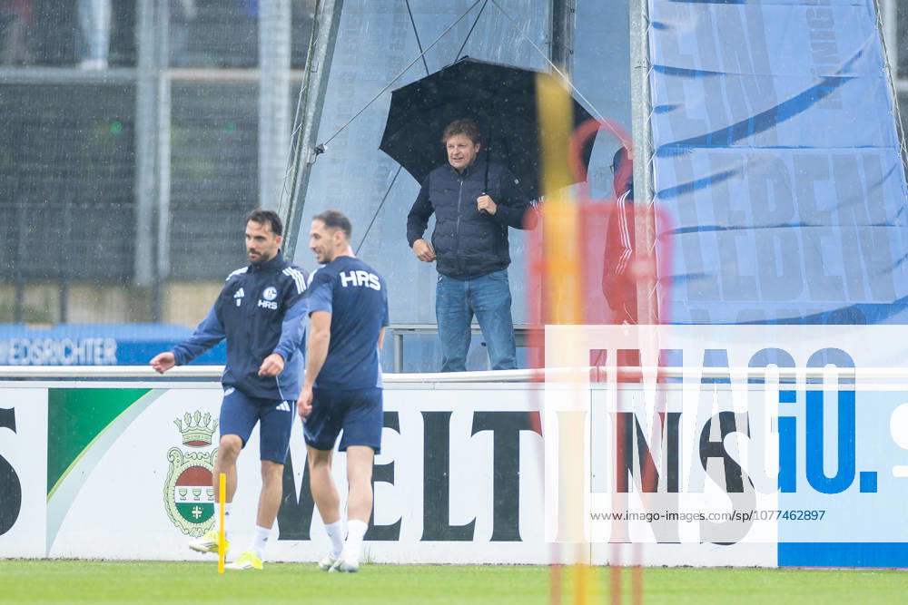 Fussball, Training des FC Schalke 04. Direktor Profifussball Youri Mulder (FC Schalke 04) beobachtet das Training mit einem grossen Regenschirm. Gelsenkirchen Trainingsgelände FC Schalke 04 NRW Deutschland xRHR-FOTO YYx