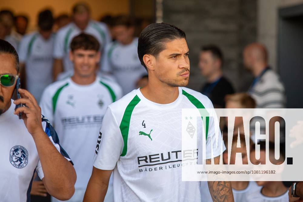 Kevin Diks ( 4; Borussia Mönchengladbach) läuft konzentriert mit dem Team auf das Spielfeld in Velbert ein. Im Hintergrund sind weitere Spieler von Borussia Mönchengladbach sowie Zuschauer und Kinder zu sehen. Kevin Diks ( 4; Borussia Mönchengladbach) beim Einlaufen in Velbert