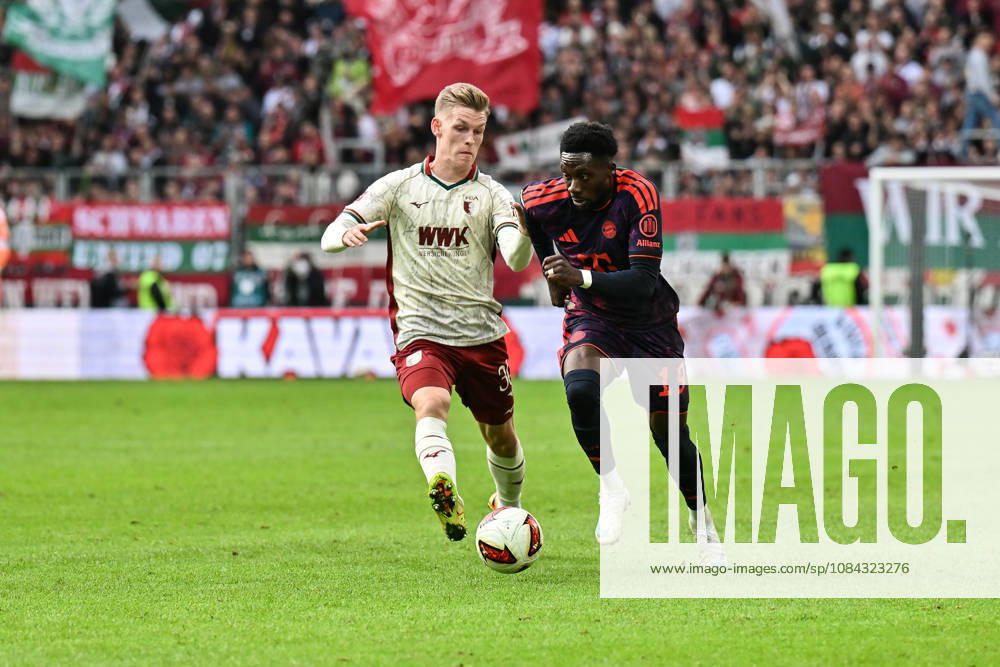 AUGSBURG, GERMANY; 10. OCTOBER: tackle between Anton KADE (FC Augsburg 30) und Alphonso DAVIES (FC Bayern Munich 19) during the Bundesliga Match between FC Augsburg vs. FC Bayern Munich at Matchday 5 at WWK-Arena DFL REGULATIONS PROHIBIT ANY USE OF PHOTOGRAPHS AS IMAGE SEQUENCES AND OR QUASI-VIDEO