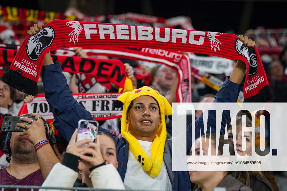 Deutschland: Fussball UEFA Conference League 2026 - 2027, 1. Spieltag - SC Freiburg vs FK Jablonec - Europa-Park-Stadion (Freiburg): Fan des SC Freiburg mit gelber Pikachu-Mütze hält einen rot-schwarzen Fanschal mit der Aufschrift FREIBURG und Vereinswappen über den Kopf. Porträt eines Anhängers auf der Tribüne des Europa-Park-Stadions beim UEFA Conference League-Spiel gegen FK Jablonec. SC Freiburg, Fussball, Europapokal, Fans, Zuschauer, Fankultur, Fanschal, Fanartikel, Merchandising, Pikachu, PokÃ mon, Kostüm, Verkleidung, Vereinsfarben, Heimfans, Stimmung, Begeisterung, Supporter, Smartphone, Stadion.