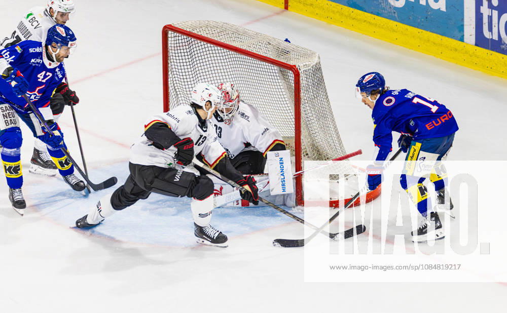 Ice hockey, Eishockey National League Regular Season - EHC Kloten vs Lausan Kloten, Switzerland, 20th Oct 2026: 14 Mischa Ramel (Kloten) puts the puck into the slot in front of goaltender 33 Kevin Pasche (Lausanne). 47 Joona Luoto (Kloten) is in front of the net, as is 13 Basile Sansonnens (Lausanne).