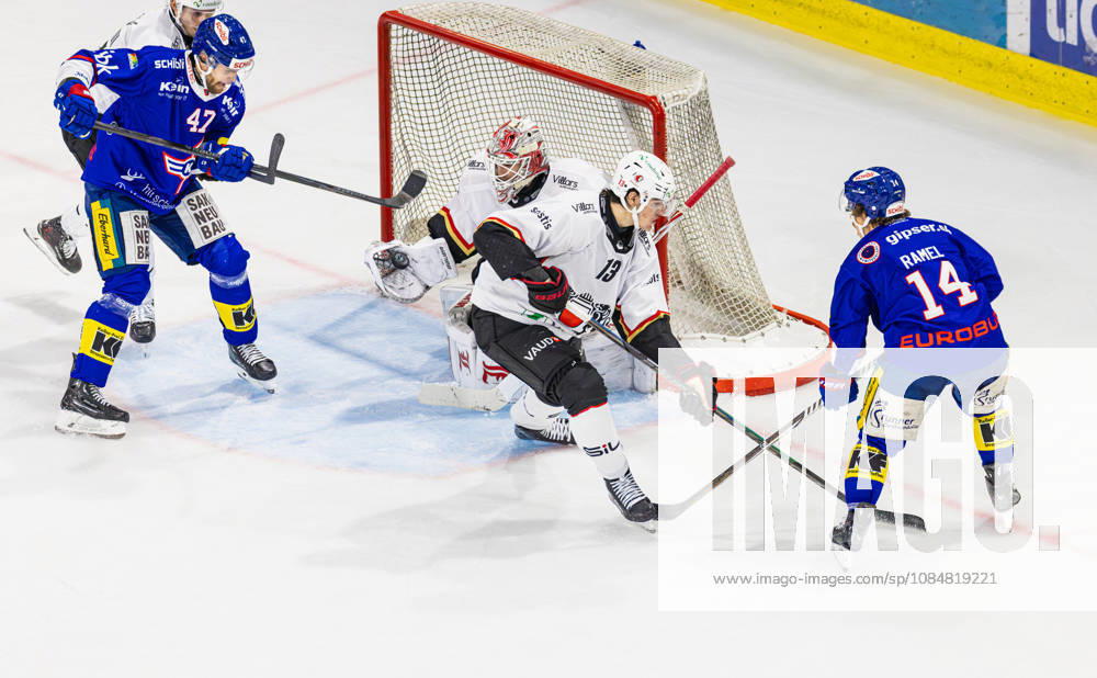 Ice hockey, Eishockey National League Regular Season - EHC Kloten vs Lausan Kloten, Switzerland, 20th Oct 2026: 14 Mischa Ramel (Kloten) puts the puck into the slot in front of goaltender 33 Kevin Pasche (Lausanne). 47 Joona Luoto (Kloten) is in front of the net, as is 13 Basile Sansonnens (Lausanne).