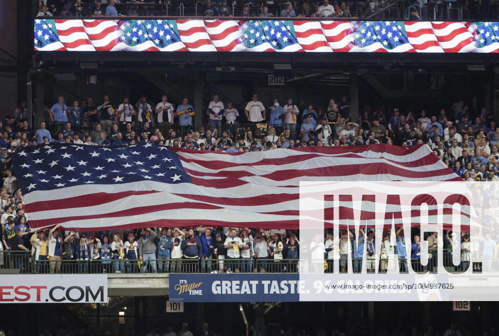 An American flag is unfurled in the stands for the singing of the National Anthem before the start of game one of the 2026 MLB, Baseball Herren, USA World Series between Milwaukee Brewers and the Tampa Bay Rays at American Family Field in Milwaukee, Wisconsin, on Friday, October 23, 2026. MIL20261023702 TANNENxMAURY