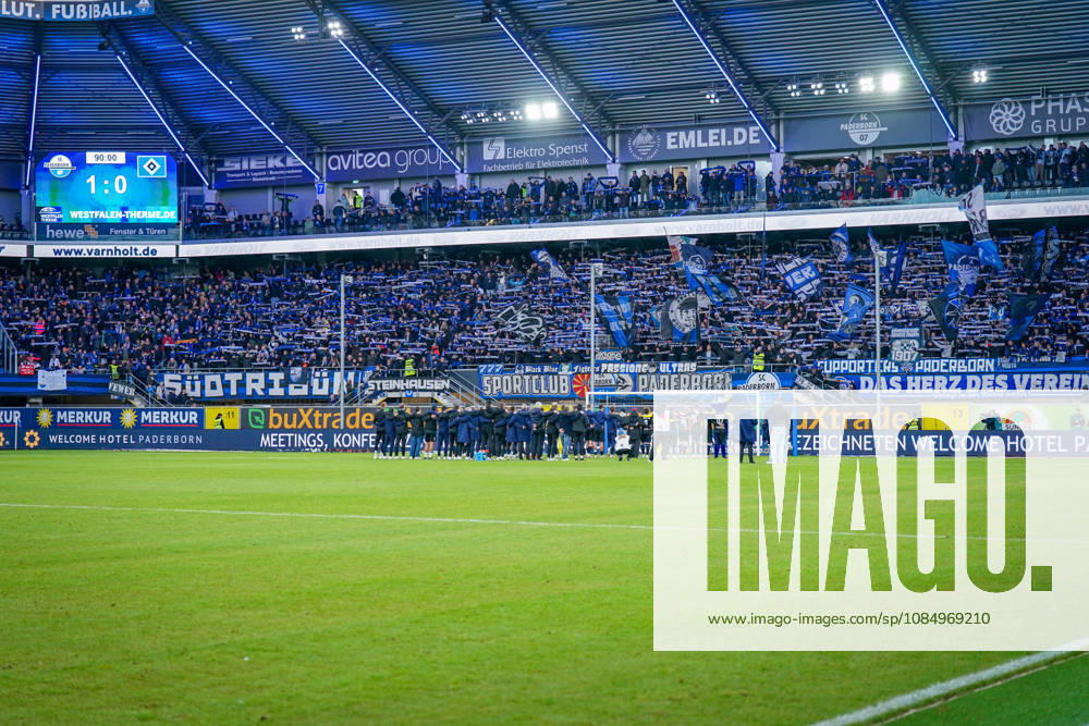 Deutschland: Fussball Bundesliga 2026 - 2027, 7. Spieltag - SC Paderborn vs Hamburger SV - Home-Deluxe-Arena (Paderborn): Heimsieg des SC Paderborn 07 gegen den Hamburger SV (HSV). Spieler, Trainer und Betreuer feiern nach Spielende gemeinsam mit den Heimfans vor der Fankurve der Home-Deluxe-Arena. Siegesfeier, Jubel, Mannschaft, Mannschaftsfoto von hinten, Schulterschluss, Fans, Ultras, Zuschauer, Tribüne, Fahnen, Schals, Fangesänge, Emotionen, Bundesliga, Fussball, Heimsieg, Sportstätte, Innenansicht, Totale, Hintertorperspektive, Tor, Fanbanner, Fankultur, Zusammenhalt.