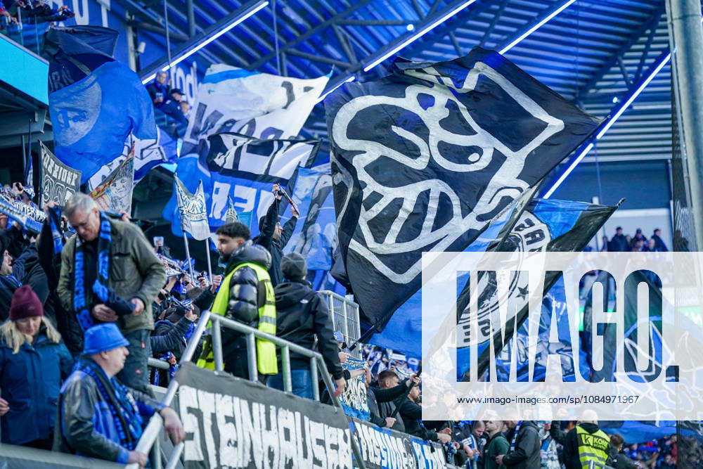 Deutschland: Fussball Bundesliga 2026 - 2027, 7. Spieltag - SC Paderborn vs Hamburger SV - Home-Deluxe-Arena (Paderborn): Heimfans des SC Paderborn 07 feiern auf der Tribüne der Home-Deluxe-Arena den Heimsieg gegen den Hamburger SV (HSV). Zahlreiche grosse blau-schwarz-weisse Fahnen mit Vereinswappen und Fanmotiven. Fans, Ultras, Fanszene, Fankultur, Fankurve, Fanblock, Zuschauer, Fahnenmeer, Jubel, Siegesfeier, Stimmung, Emotionen, Support, Fangesänge, Tribüne, Bundesliga, Fussball, Sportstätte, Innenansicht, Stadiondach, Flutlicht, Sicherheitsdienst, Ordnungsdienst.