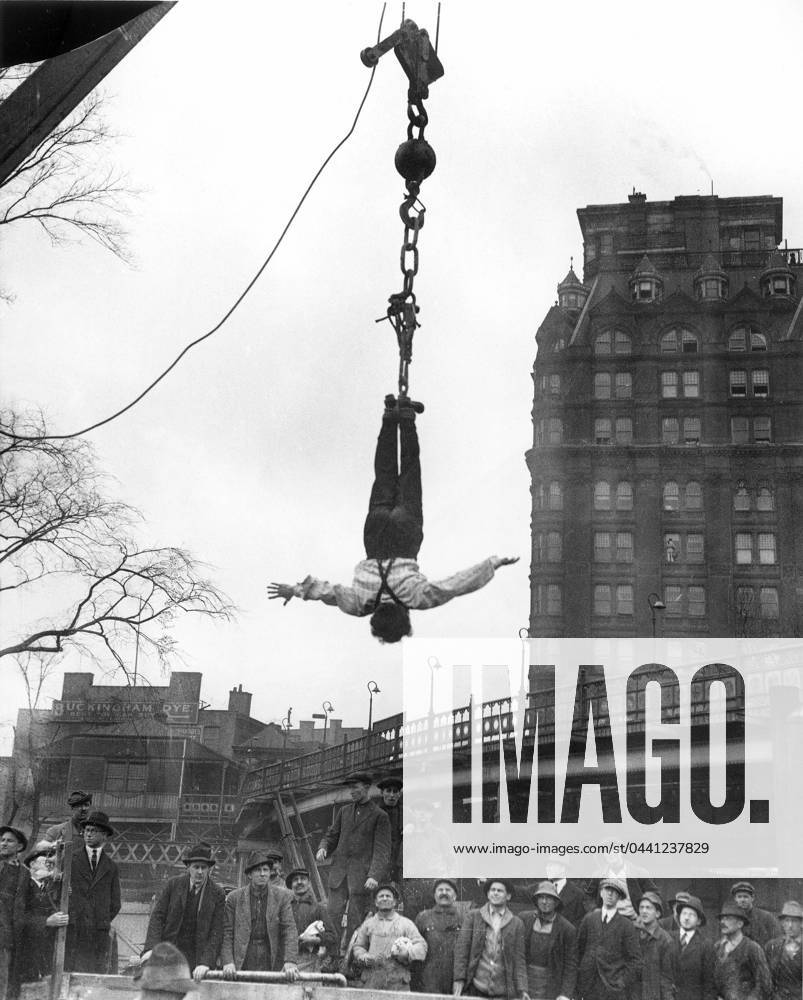HARRY HOUDINI (1874-1926). American magician. Houdini at finish of stunt of releasing himself from a straitjacket while suspended in midair; photographed in 1916.