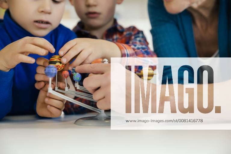 IMAGO Creative: Bildung, Wissenschaftserziehung Pre-school teacher and boys exploring solar system model in kindergarten model released Symbolfoto property released MFF04125