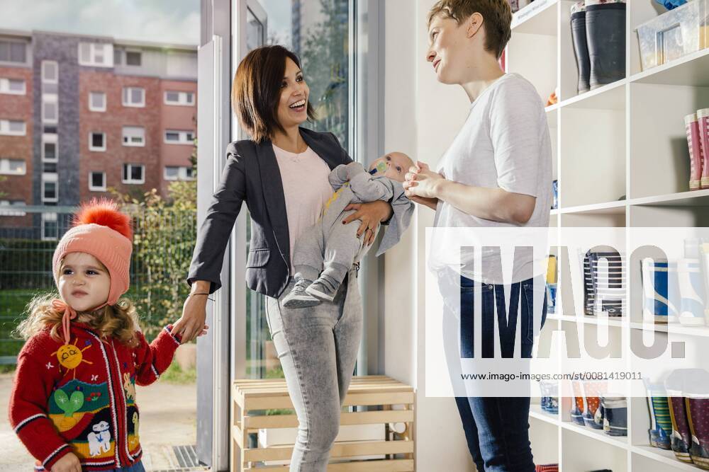 Smiling mother with baby bringing girl to kindergarten model released Symbolfoto property released MFF04121