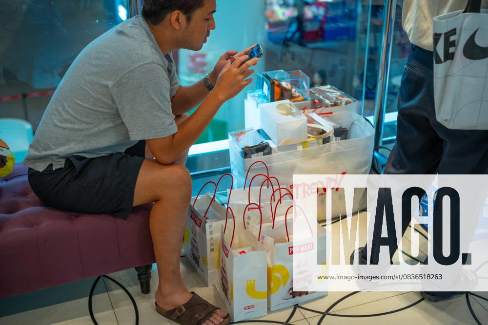 A customer sits with a few bags of toys next to a Pop Mart shop at the Siam Center. The store opened on July 17th, 2025. Bangkok Thailand - ZUMAs197 20251005_aaa_s197_747