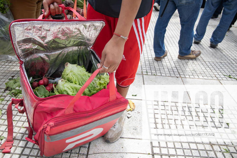 A Delivery Worker Packs Food into His Backpack.During the farmersâ€⠢ protest at Plaza de Mayo, fresh produce is freely distributed to spotlight the sectorâ€⠢s production and consumption crisis. Buenos Aires Argentina - ZUMAp265 20251016_zip_p265_012