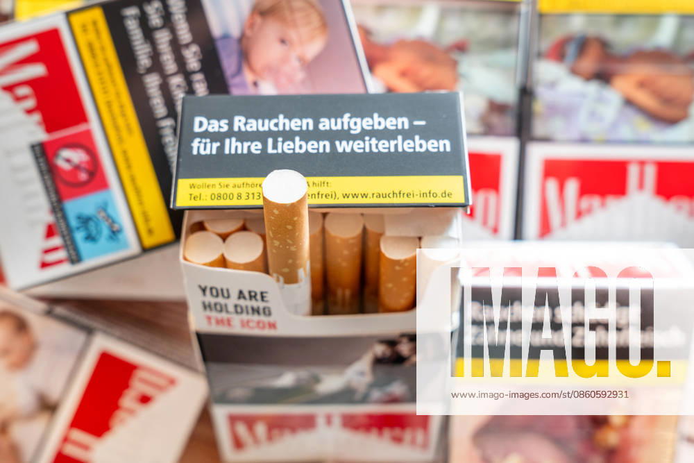 Mehrere Schachteln Zigaretten und eine geöffnete Zigarettenschachtel mit Warnhinweisen (wie: das Rauchen aufgeben - für Ihre Lieben weiterleben) zum Rauchstopp. Das Bild steht für die Gesundheitsrisiken des Rauchens, Nikotinabhängigkeit sowie Prävention und die Motivation, mit dem Rauchen aufzuhören und die Belastung durch Erkrankungen