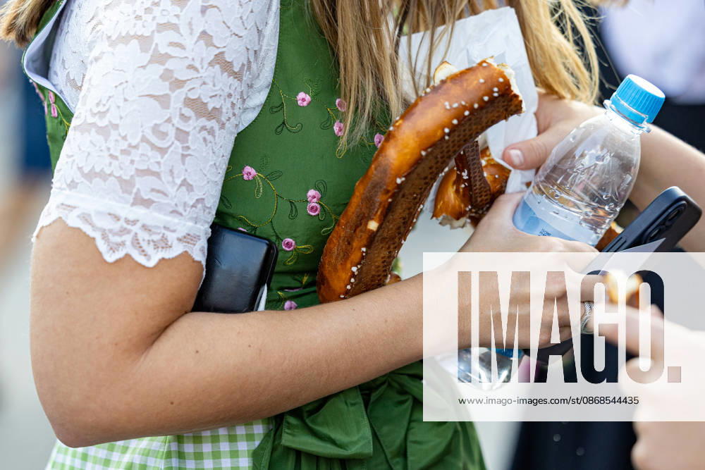 Oktoberfest 2026 in München 04.10.2026: Eine Besucherin im Dirndl hält eine Brezn und eine Flasche Wasser auf dem Festgelände. Das 191. Oktoberfest fand 2026 vom 19. September bis 4. Oktober auf der Theresienwiese statt. Das Münchner Oktoberfest zählt zu den größten Volksfesten der Welt und zieht jährlich Millionen Besucher aus Deutschland und dem Ausland an. Muenchen Theresienwiese Bayern Deutschland