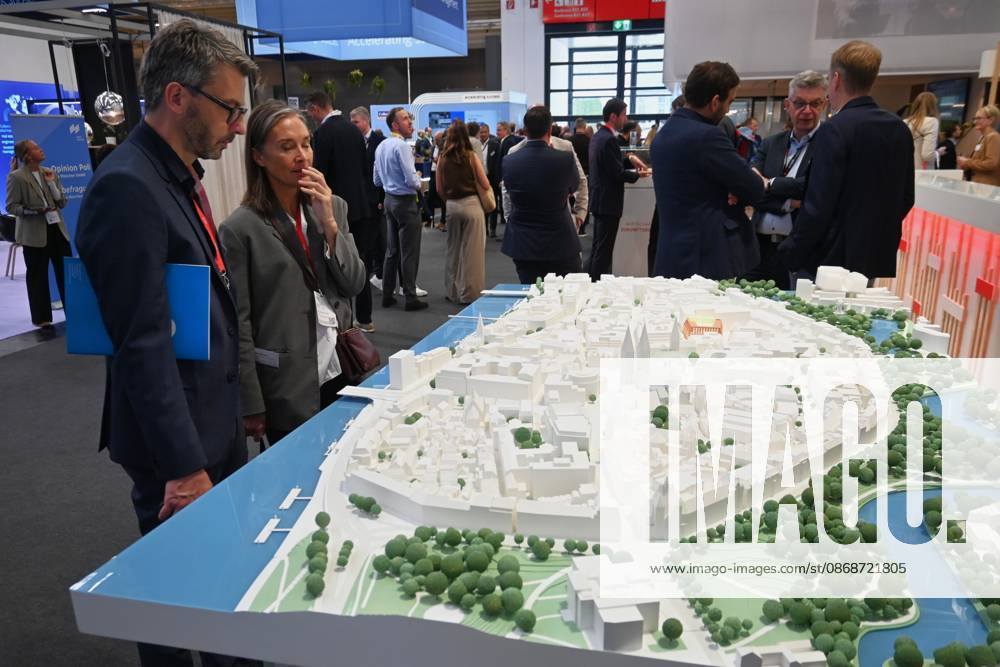 Die EXPO REAL 2026 findet aktuell auf dem Messegelände der Messe München statt. Sie ist Europas grösste internationale Fachmesse für Immobilien, Investitionen und Infrastruktur. Foto: Besucher betrachten an einem Messestand ein Modell.