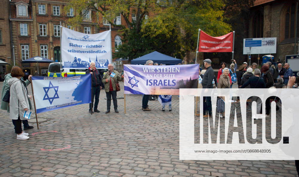 Flensburg, Schleswig-Holstein Flensburg gedenkt den Opfern des 7. Oktober 2023. Hier: Personen entfalten Transparente mit farblich weiß-blauen Hintergrund. LInks: Judenstern und Text Gegen jeden Antisemitismus, immer und überall! Für Respekt, Menschlichkeit und Zusammenhalt. Mitte: Jüdisches Leben in Flensburg. Sicher - sichtbar - selbstverständlich. Rechts Wir stehen an der Seite Israels. Rechts außen (Transparent in Rot mit weißer Schrift) 7. Oktober 2023, Terroranschlag auf Israel. 1200 Ermordete, 250 Verschleppte.Aufnahme vom 07.10.2026, Flensburg