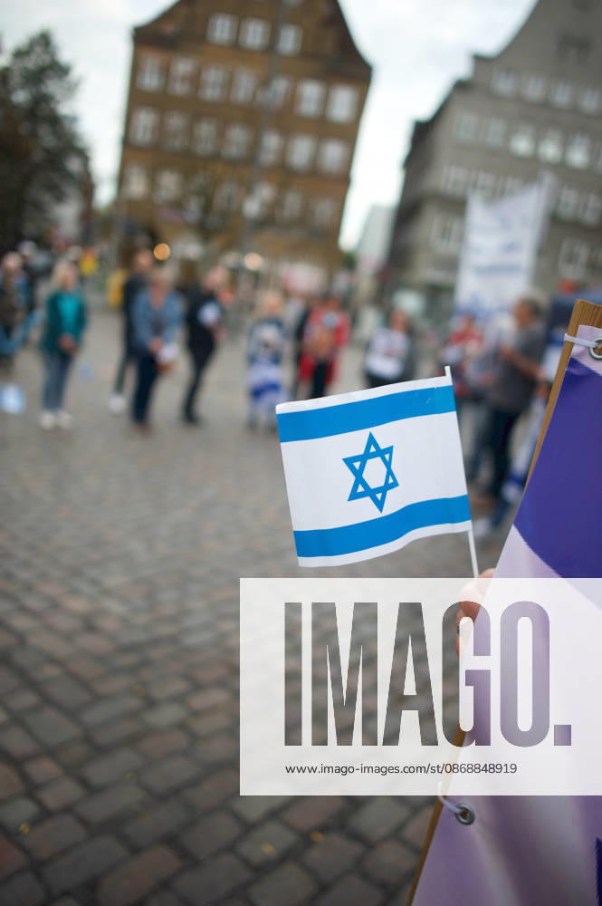 Flensburg, Schleswig-Holstein Flensburg gedenkt den Opfern des 7. Oktober 2023. Teilnehmer versammeln sich auf dem Südermarkt. Vorner Pserson hält Flagge von Israel. Es werden Lieder gesungen und die Namen und Geschichten einzelner Opfer des Terroranschlages vorgelesen. Aufnahme vom 07.10.2026, Flensburg