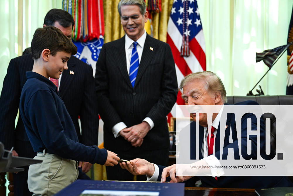 WASHINGTON, DC - OCT. 7: United States President Donald J Trump hands a challenge coin to a child during an announcement on Trump Accounts in the Oval Office of the White House in Washington, DC, USA, on Wednesday, October 7, 2026. Standing behind the President, from left to right: Frank J Bisignano, Commissioner, Social Security Administration (SSA); and US Secretary of the Treasury Scott Bessent.