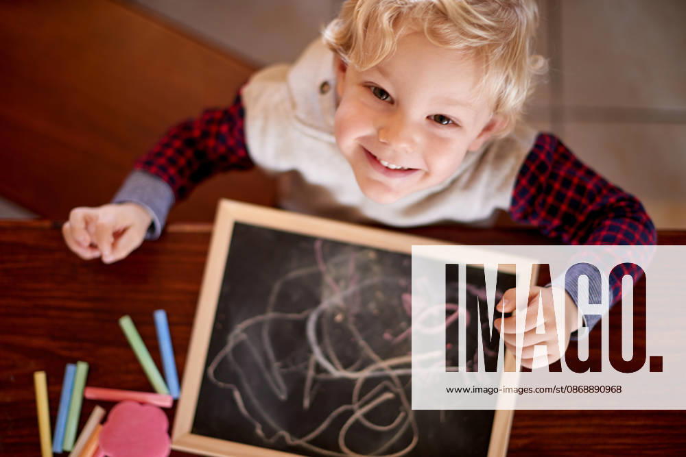 Chalk, drawing and portrait of boy at table in home for development, education or growth. Above, creative and hobby with child in apartment for hand eye coordination, imagination and motor skills. model released property released