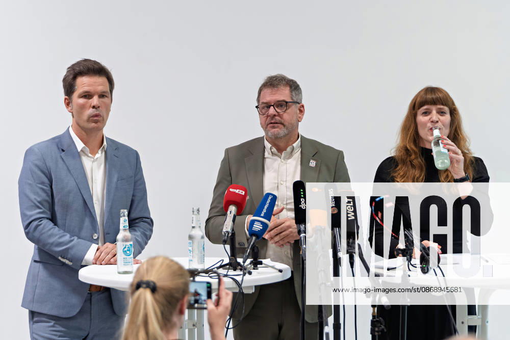 Berlin, 08.10.2026: Werner Graf (Bündnis 90 Die Grünen, M.) spricht neben Steffen Krach (SPD, l.) beim gemeinsamen Pressestatement nach Abschluss der Vorgespräche ihrer Parteien im Foyer des Hauses der Statistik, Kerstin Wolter-Ehling (Die Linke, r.) trinkt aus einer Wasserflasche. Pressestatement von Linke, Grünen und SPD in Berlin
