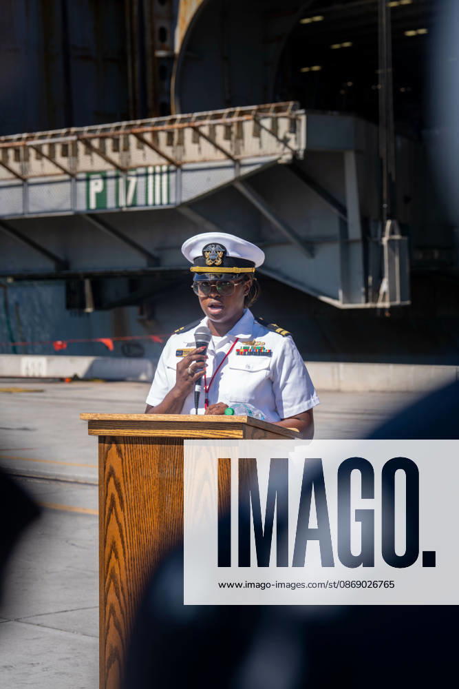 A U.S. Navy officer speaks into a microphone at a podium during the homecoming of the aircraft carrier USS Abraham Lincoln (CVN 72) at Naval Air Station North Island in Coronado, California, on October 8, 2026. Coronado United States - ZUMAg374 20261008_znp_g374_005