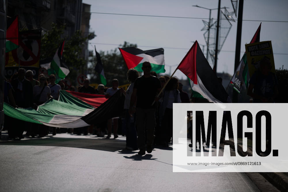 Demonstrators carrying Palestinian flags and a large Palestinian flag-shaped banner march along a city street. Athens GREECE - ZUMAx103 20261010_zip_x103_019