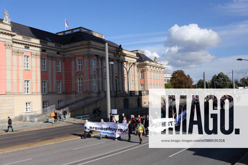Demonstranten laufen mit Bannern Brandenburg Prüf! sowie Prüf heute. Schütz morgen! am Landtag während einer Demonstration für die Überprüfung rechtsextremer Parteien durch das Bundesverfassungsgericht, Potsdam, 10. Oktober 2026. Prüf-Demo in Potsdam