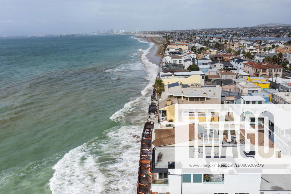 The Long Beach Peninsula is facing severe, structural devastation as Tropical Storm Rachel batters the Southern California coast. Driven by a developing El Nino pattern, this is the fourth major storm system to slam the shoreline in six weeks. Waves and unusually high tides have shattered a 30-foot section of the protective wooden bulkhead, completely shredding the historic boardwalk and allowing seawater to surge directly onto interior streets. Flooding has swamped coastal neighborhoods, forcing mandatory evacuations along oceanfront blocks like Seaside Walk. Emergency crews are working to stack thousands of sandbags and reinforce coastal defenses, but city inspectors have already been forced - ZUMAr19_ 20261011_new_r19_128