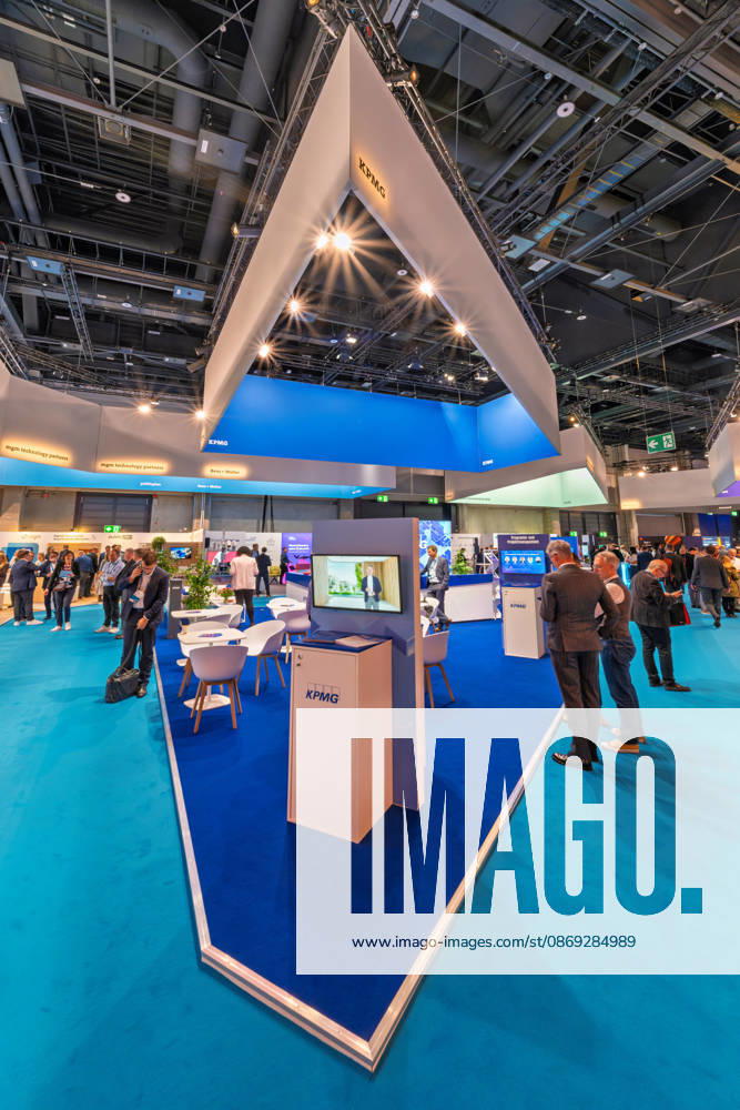 Berlin, 13.10.2026: Der Messestand von KPMG mit seinem spitz zulaufenden, beleuchteten Deckenaufbau auf der Smart Country Convention in der Halle hub27. Beratungsunternehmen wie KPMG begleiten Bund, Länder und Kommunen bei der Digitalisierung ihrer Verwaltungsprozesse. Die Smart Country Convention (SCCON) ist die Kongressmesse für die Digitalisierung des öffentlichen Sektors und wird vom Digitalverband Bitkom gemeinsam mit der Messe Berlin veranstaltet. Vom 13. bis 15. Oktober 2026 treffen sich in der Halle hub27 Vertreter aus Bund, Ländern und Kommunen mit Unternehmen der Digitalwirtschaft, um über digitale Verwaltung, Smart City und digitale Souveränität zu diskutieren. KPMG-Stand auf der Smart Country Convention