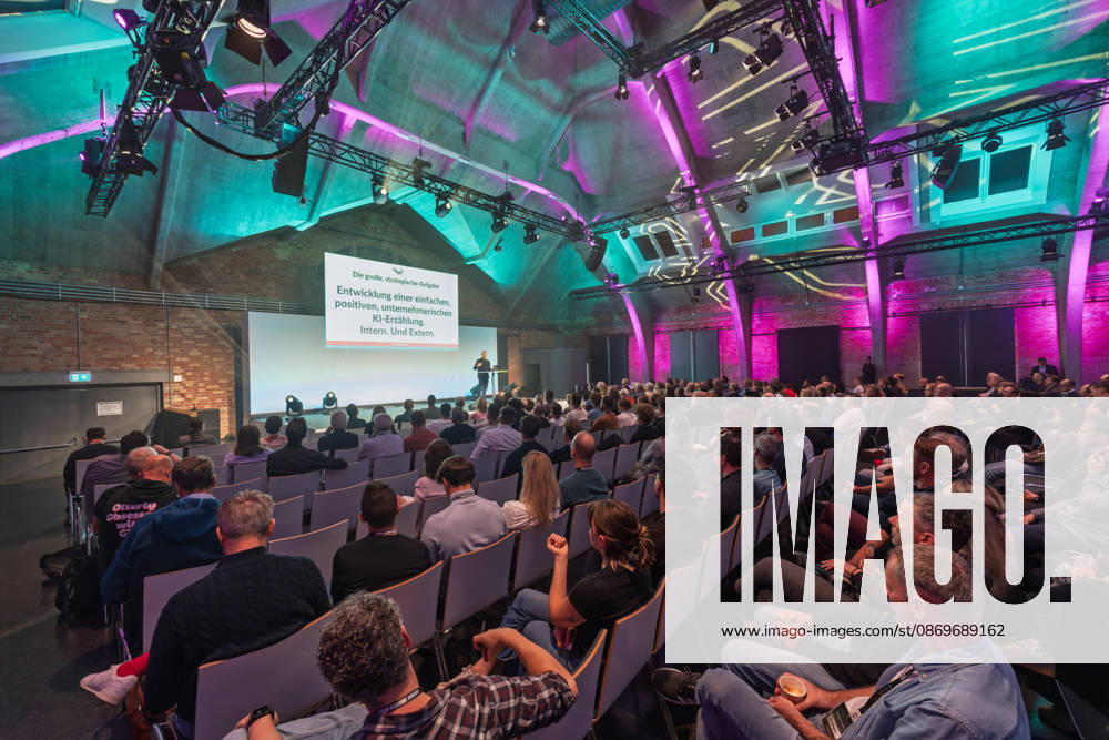 Berlin, 16.10.2026: Zahlreiche Zuhörer verfolgen in der violett und türkis beleuchteten Halle des WECC den Vortrag des Publizisten und Digital-Vordenkers Sascha Lobo auf der NeulandPro Connect 2026. Die zweitägige KI-Konferenz NeulandPro Connect 2026 findet am 16. und 17. Oktober im Westhafen Event & Convention Center (WECC) in Moabit statt, einem historischen Speichergebäude am Berliner Westhafen. Veranstalter ist NeulandPro, eine Bildungs- und Medienmarke rund um Künstliche Intelligenz. Mit Vorträgen, Workshops und Hackathons richtet sich die Konferenz vor allem an kleine und mittelständische Unternehmen, Gründer und Führungskräfte, die KI praktisch einsetzen wollen; erwartet werden bis zu 1.000 Gäste. NeulandPro Connect 2026 -