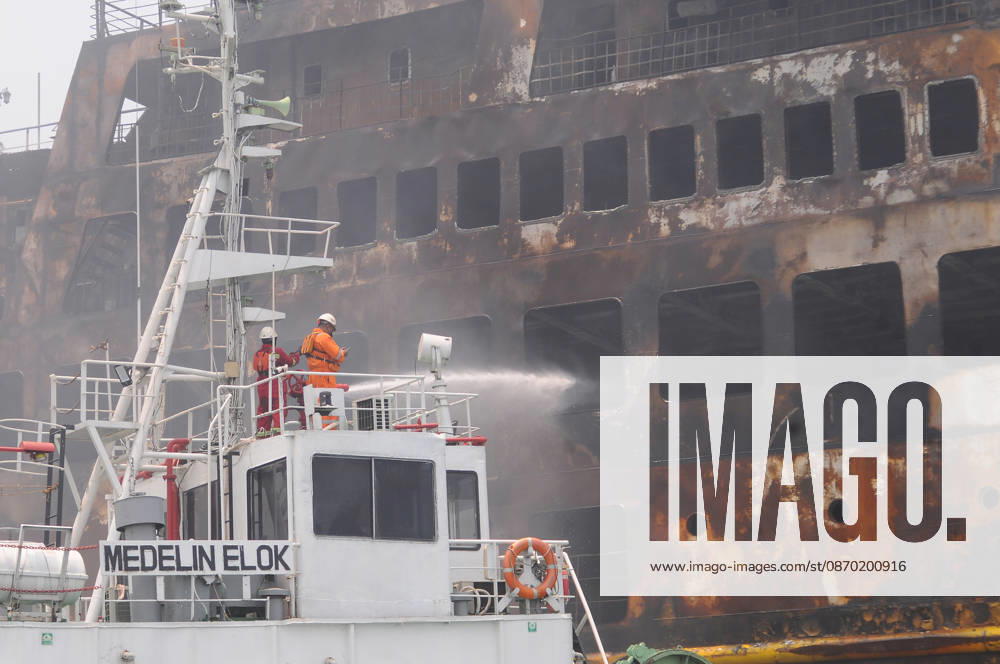 Efforts are underway to extinguish a fire that broke out on a passenger ferry in Indonesia s Cilegon PELABUHAN MERAK, CILEGON, INDONESIA - OCTOBER 21: Fireboats take turns spraying water onto the passenger ferry KMP Batumandi to cool down the vessel after it caught fire while preparing to dock off Merak Port in Cilegon, Banten, Indonesia on Wednesday, October 21, 2026. The vessel caught fire on Tuesday, October 20, and rescue operations remain underway as the ship continues to emit smoke. Water is continuously sprayed to cool the vehicle deck containing numerous cars, motorcycles, buses, and trucks, while authorities confirm no fatalities have been reported. Dasril Roszandi Anadolu Pelabuhan Merak Indonesia. Editorial use only. Please get