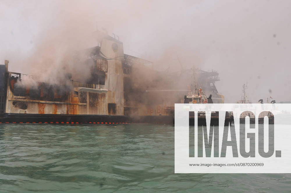Efforts are underway to extinguish a fire that broke out on a passenger ferry in Indonesia s Cilegon PELABUHAN MERAK, CILEGON, INDONESIA - OCTOBER 21: Fireboats take turns spraying water onto the passenger ferry KMP Batumandi to cool down the vessel after it caught fire while preparing to dock off Merak Port in Cilegon, Banten, Indonesia on Wednesday, October 21, 2026. The vessel caught fire on Tuesday, October 20, and rescue operations remain underway as the ship continues to emit smoke. Water is continuously sprayed to cool the vehicle deck containing numerous cars, motorcycles, buses, and trucks, while authorities confirm no fatalities have been reported. Dasril Roszandi Anadolu Pelabuhan Merak Indonesia. Editorial use only. Please get