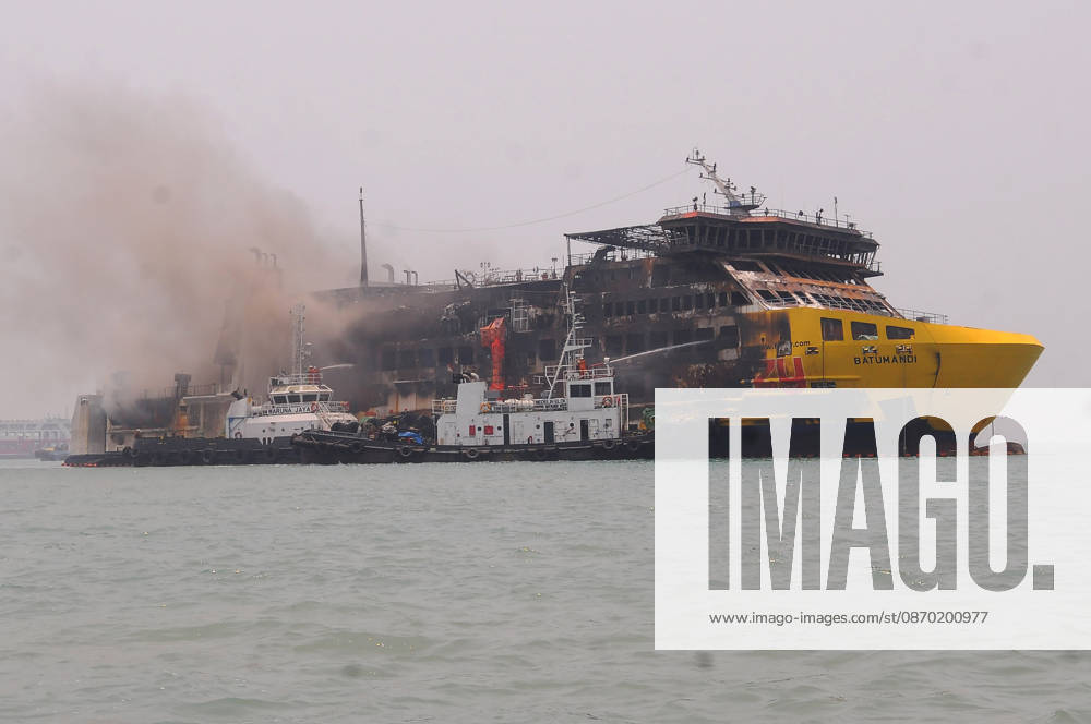 Efforts are underway to extinguish a fire that broke out on a passenger ferry in Indonesia s Cilegon PELABUHAN MERAK, CILEGON, INDONESIA - OCTOBER 21: Fireboats take turns spraying water onto the passenger ferry KMP Batumandi to cool down the vessel after it caught fire while preparing to dock off Merak Port in Cilegon, Banten, Indonesia on Wednesday, October 21, 2026. The vessel caught fire on Tuesday, October 20, and rescue operations remain underway as the ship continues to emit smoke. Water is continuously sprayed to cool the vehicle deck containing numerous cars, motorcycles, buses, and trucks, while authorities confirm no fatalities have been reported. Dasril Roszandi Anadolu Pelabuhan Merak Indonesia. Editorial use only. Please get