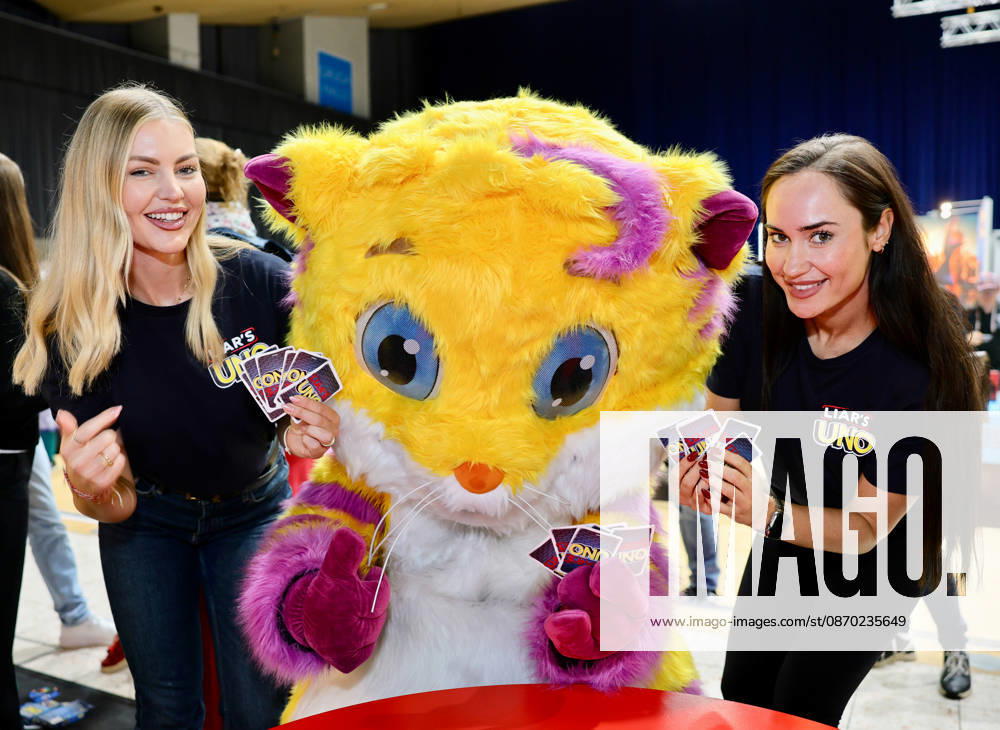 Spiel 26 Messe in Essen - Mattel stellt Neuheit UNO LIAR S Kartenspiel vor - die Models Lydia und Sorin mit Spiel-Maskottchen MEEPS Essen Grugahalle Messe NRW Deutschland