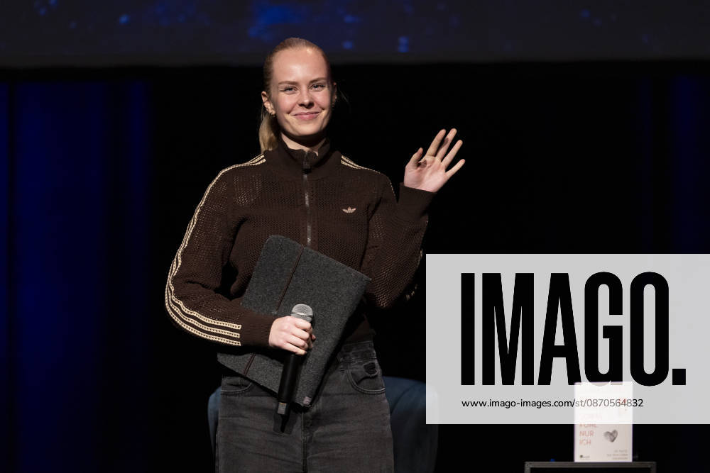 Poetry Artist, Autorin Clara LOESEL (LÖSEL) winkt laechelnd ins Publikum, bei ihrer Lesung, Previewshow zu ihrem neuen Buch ,Ich dachte, sowas fuehl nur ich, stehend, Einzelbild, Einzelfoto, im Theater am Tanzbrunnen, Koeln, am 23.10.2026.