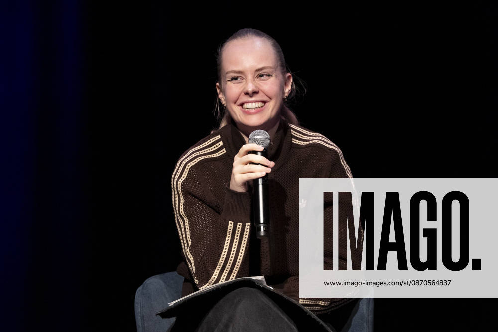 Poetry Artist, Autorin Clara LOESEL (LÖSEL) laechelnd, Lachen, bei ihrer Lesung, Previewshow zu ihrem neuen Buch ,Ich dachte, sowas fuehl nur ich, sitzend, mit Mikrofon, Einzelbild, Einzelfoto, im Theater am Tanzbrunnen, Koeln, am 23.10.2026.
