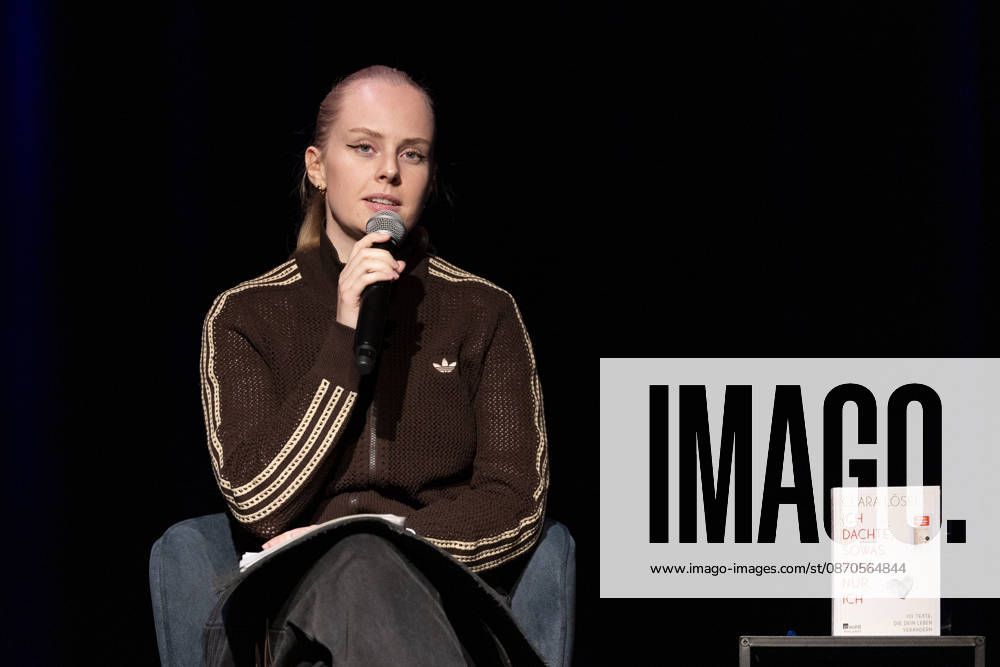 Poetry Artist, Autorin Clara LOESEL (LÖSEL) ernst, konzentriert, bei ihrer Lesung, Previewshow zu ihrem neuen Buch ,Ich dachte, sowas fuehl nur ich, sitzend, mit Mikrofon, Einzelbild, Einzelfoto, im Theater am Tanzbrunnen, Koeln, am 23.10.2026.