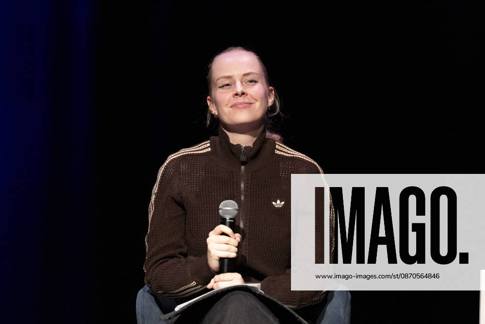 Poetry Artist, Autorin Clara LOESEL (LÖSEL) schmunzelnd, geniesst den Moment, bei ihrer Lesung, Previewshow zu ihrem neuen Buch ,Ich dachte, sowas fuehl nur ich, sitzend, mit Mikrofon, Einzelbild, Einzelfoto, im Theater am Tanzbrunnen, Koeln, am 23.10.2026.