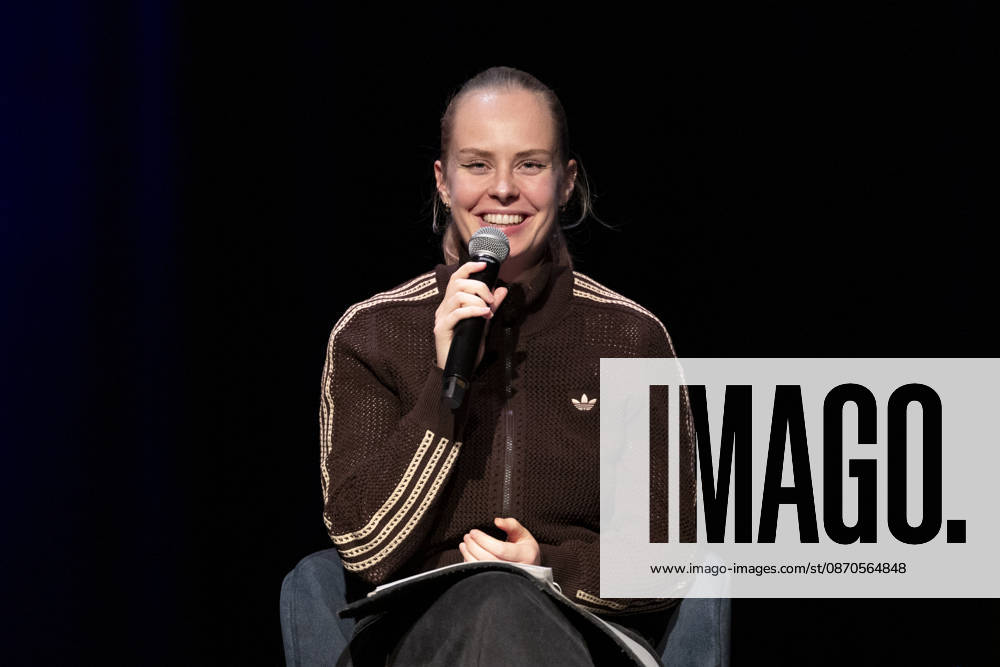 Poetry Artist, Autorin Clara LOESEL (LÖSEL) lachend, Lachen, bei ihrer Lesung, Previewshow zu ihrem neuen Buch ,Ich dachte, sowas fuehl nur ich, sitzend, mit Mikrofon, Einzelbild, Einzelfoto, im Theater am Tanzbrunnen, Koeln, am 23.10.2026.