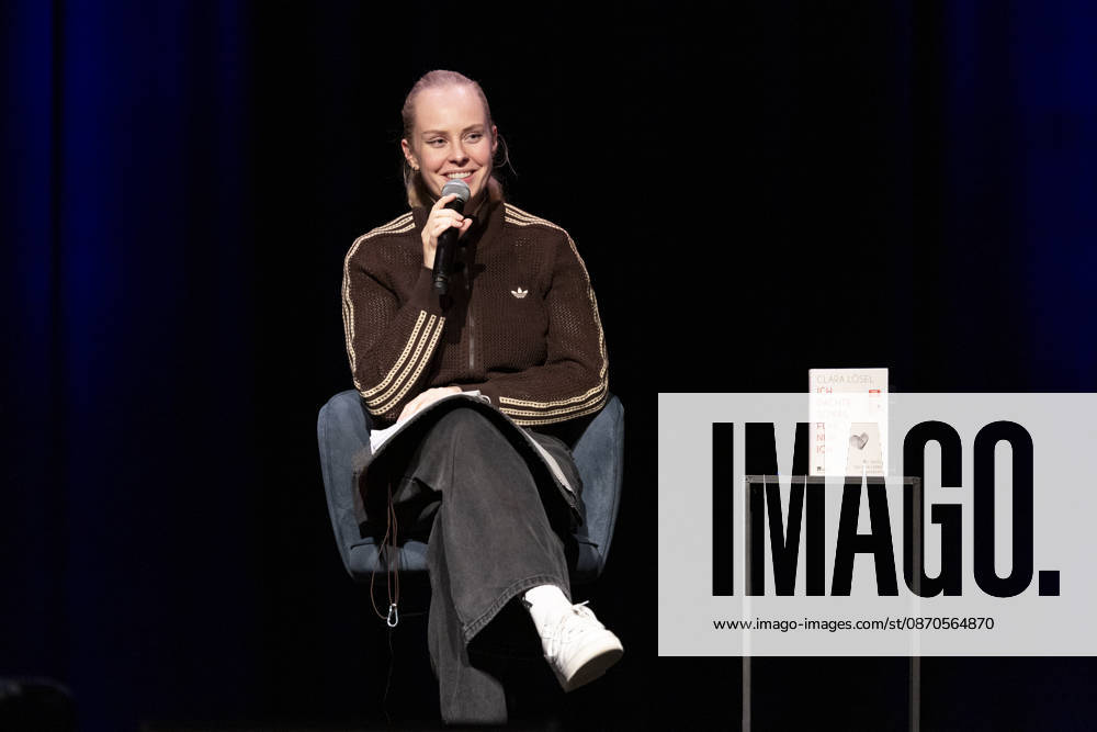 Poetry Artist, Autorin Clara LOESEL (LÖSEL) lachend, Lachen, bei ihrer Lesung, Previewshow zu ihrem neuen Buch ,Ich dachte, sowas fuehl nur ich, sitzend, mit Mikrofon, Einzelbild, Einzelfoto, im Theater am Tanzbrunnen, Koeln, am 23.10.2026.