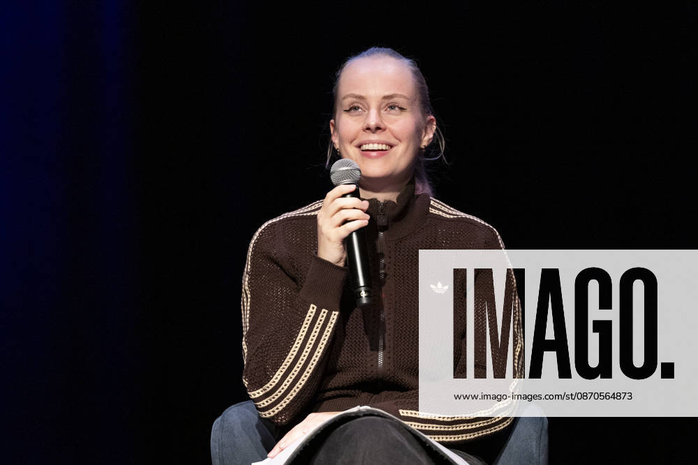 Poetry Artist, Autorin Clara LOESEL (LÖSEL) lachend, Lachen, bei ihrer Lesung, Previewshow zu ihrem neuen Buch ,Ich dachte, sowas fuehl nur ich, sitzend, mit Mikrofon, Einzelbild, Einzelfoto, im Theater am Tanzbrunnen, Koeln, am 23.10.2026.